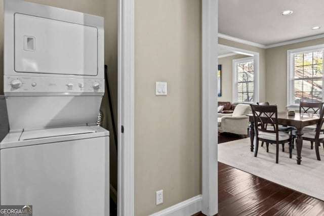 washroom with stacked washer and dryer, crown molding, and dark wood-type flooring