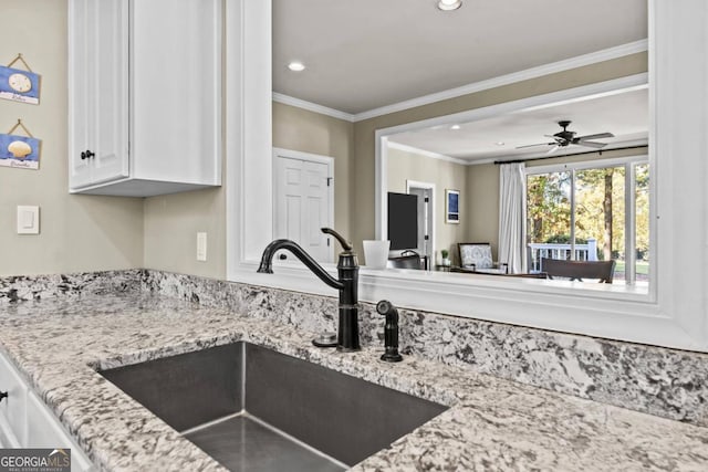 kitchen with crown molding, sink, ceiling fan, light stone countertops, and white cabinetry