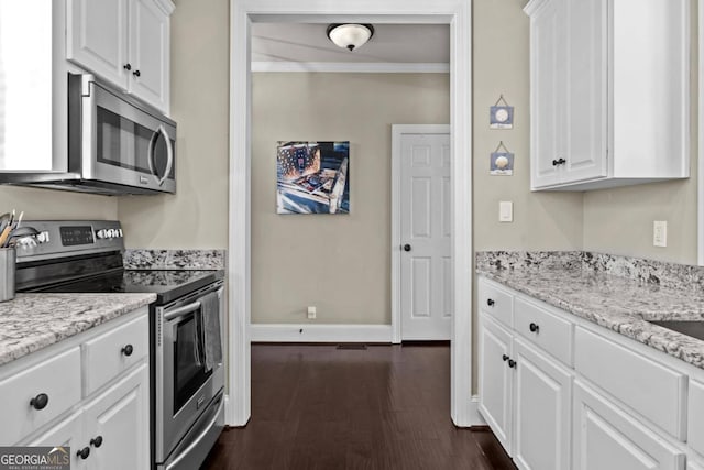 kitchen with light stone countertops, white cabinets, dark wood-type flooring, and appliances with stainless steel finishes