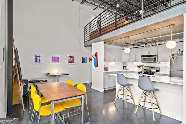 kitchen featuring decorative light fixtures, a breakfast bar area, stainless steel appliances, and decorative backsplash