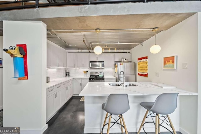 kitchen with sink, white cabinetry, decorative light fixtures, appliances with stainless steel finishes, and a kitchen breakfast bar