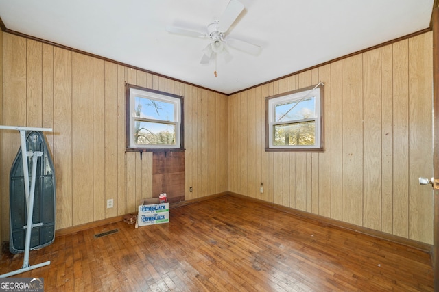 spare room featuring hardwood / wood-style flooring, a wealth of natural light, wooden walls, and ceiling fan