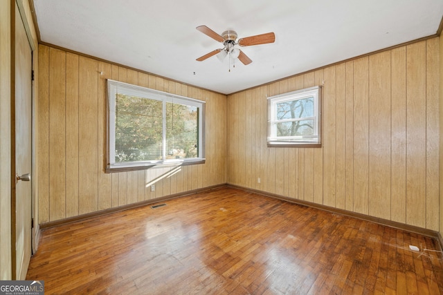 spare room featuring hardwood / wood-style flooring, ceiling fan, and wooden walls