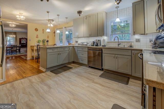 kitchen with appliances with stainless steel finishes, light hardwood / wood-style floors, hanging light fixtures, and sink