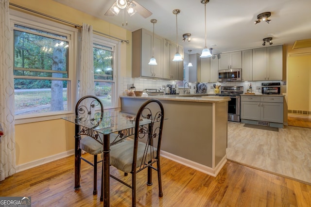 kitchen with backsplash, kitchen peninsula, gray cabinets, and appliances with stainless steel finishes