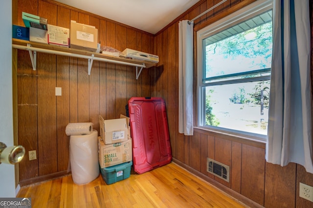 laundry area with wood walls, light wood-type flooring, and a wealth of natural light