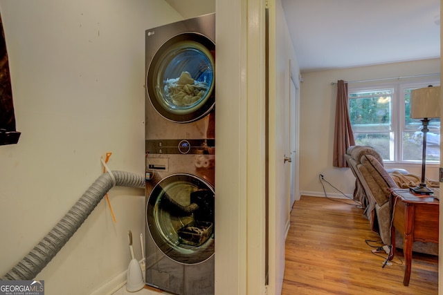 clothes washing area with stacked washing maching and dryer and light hardwood / wood-style flooring