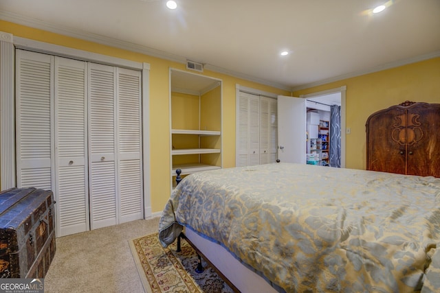 bedroom with multiple closets, crown molding, and carpet