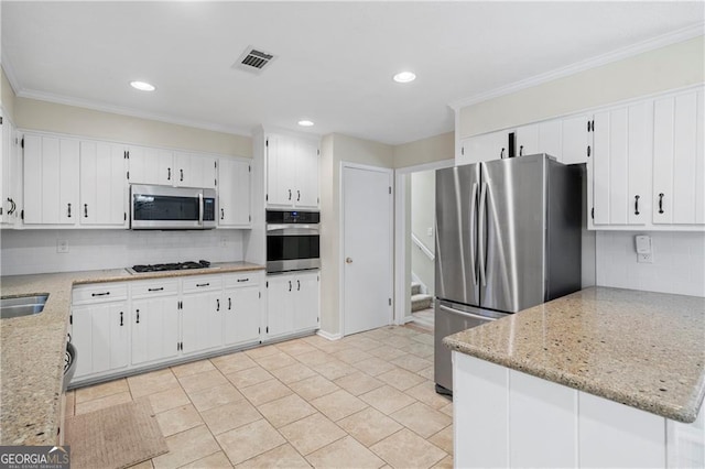 kitchen featuring light stone countertops, kitchen peninsula, appliances with stainless steel finishes, white cabinets, and ornamental molding