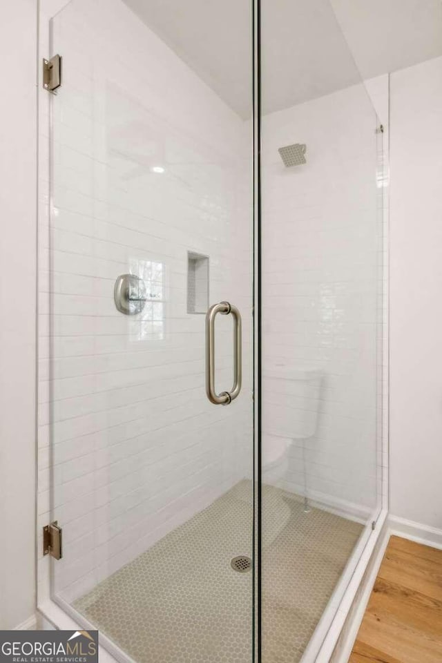 bathroom with hardwood / wood-style floors and an enclosed shower