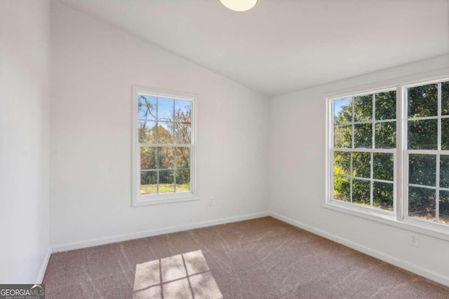 carpeted spare room with vaulted ceiling