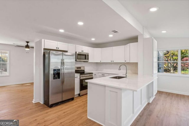 kitchen with white cabinets, sink, stainless steel appliances, and light hardwood / wood-style flooring