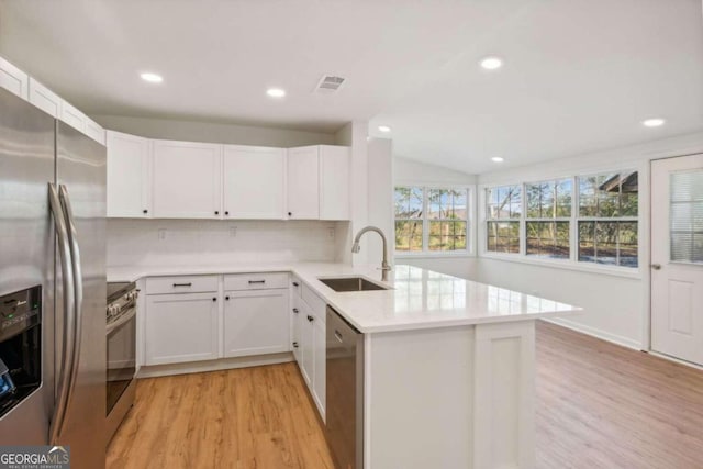 kitchen with white cabinetry, sink, stainless steel appliances, light hardwood / wood-style flooring, and kitchen peninsula