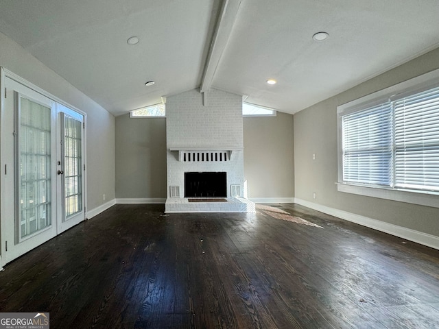 unfurnished living room with lofted ceiling with beams, dark hardwood / wood-style flooring, a fireplace, and french doors