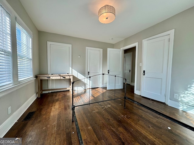 unfurnished bedroom featuring dark hardwood / wood-style flooring and multiple windows