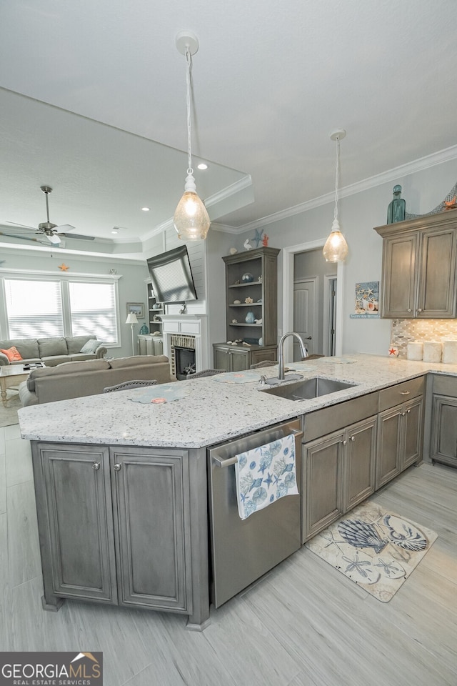 kitchen featuring pendant lighting, sink, stainless steel dishwasher, ceiling fan, and a fireplace