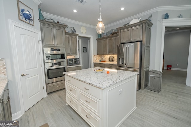 kitchen featuring decorative backsplash, ornamental molding, appliances with stainless steel finishes, decorative light fixtures, and a kitchen island