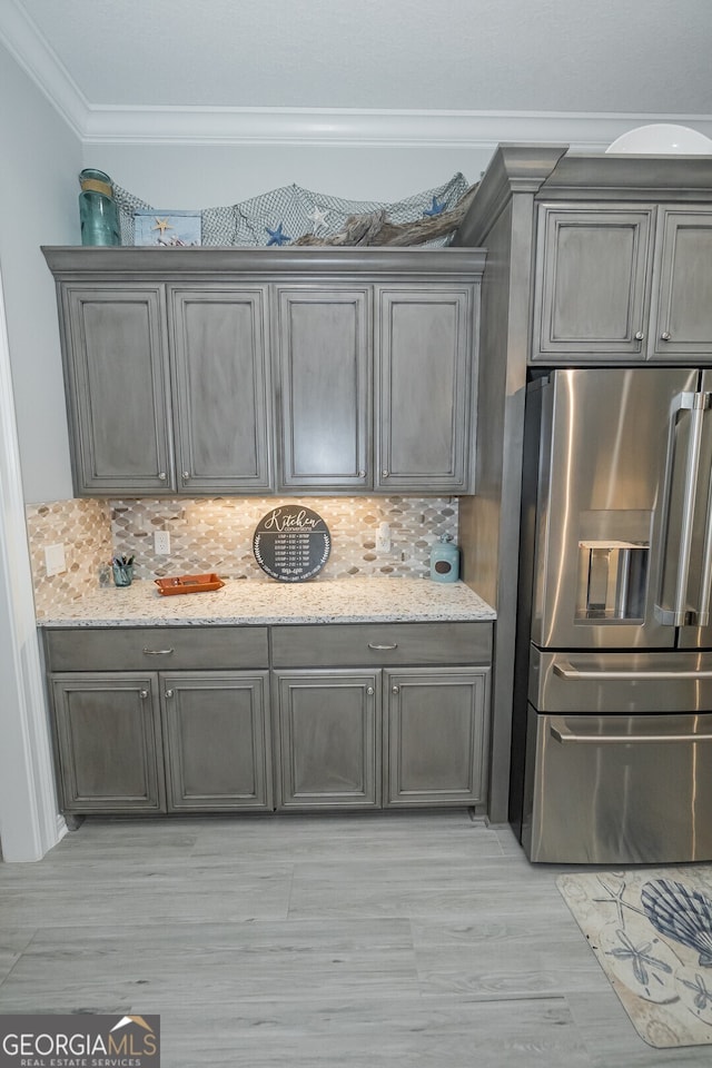 kitchen featuring tasteful backsplash, stainless steel fridge with ice dispenser, crown molding, and light stone countertops