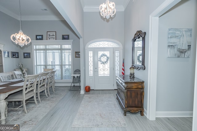 entrance foyer with crown molding, light hardwood / wood-style floors, and a notable chandelier