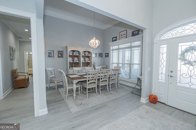 foyer featuring a high ceiling, light hardwood / wood-style floors, an inviting chandelier, and crown molding