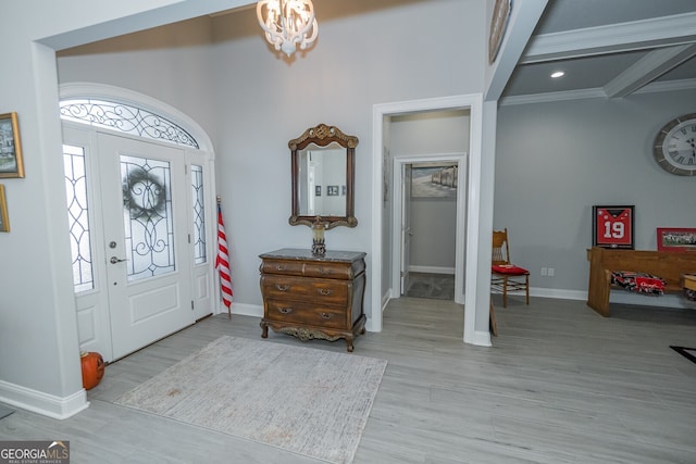 entrance foyer with beamed ceiling, light hardwood / wood-style floors, and a notable chandelier