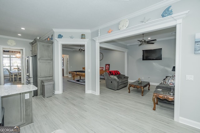 living room with crown molding, ceiling fan, and light wood-type flooring