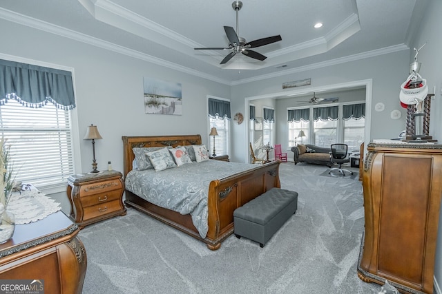 carpeted bedroom with a raised ceiling, multiple windows, ornamental molding, and ceiling fan