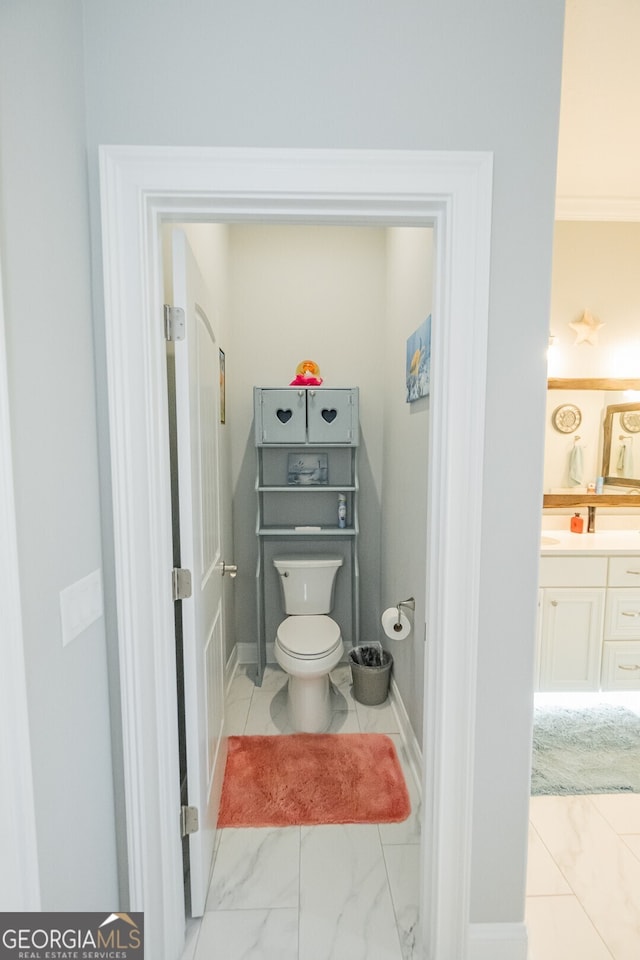 bathroom featuring toilet, vanity, and ornamental molding