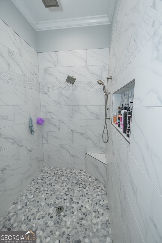 bathroom with a tile shower and crown molding