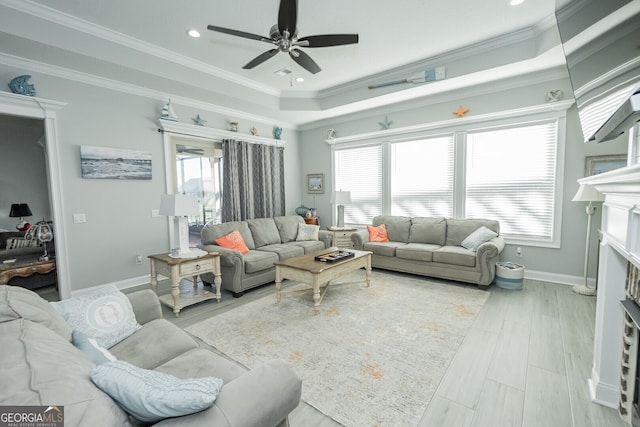 living room with ceiling fan, light wood-type flooring, crown molding, and a tray ceiling