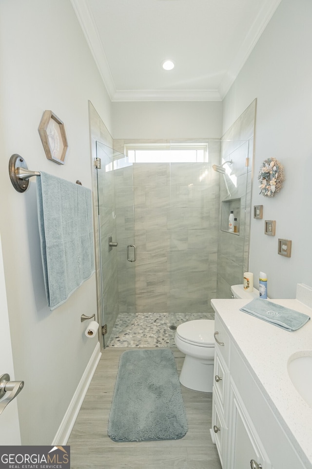 bathroom featuring vanity, hardwood / wood-style flooring, toilet, ornamental molding, and walk in shower