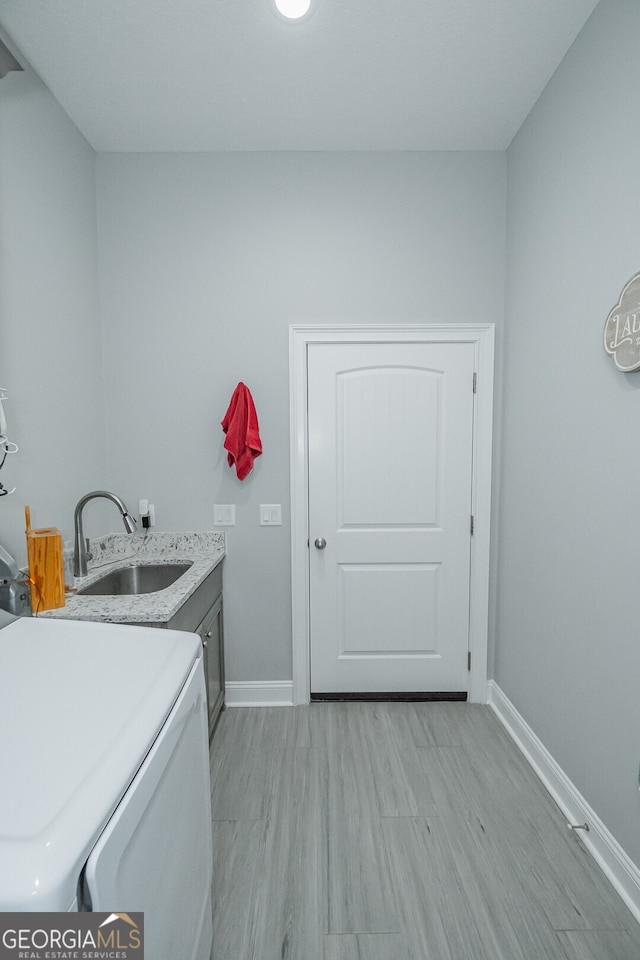 washroom with cabinets, washer / dryer, light hardwood / wood-style flooring, and sink