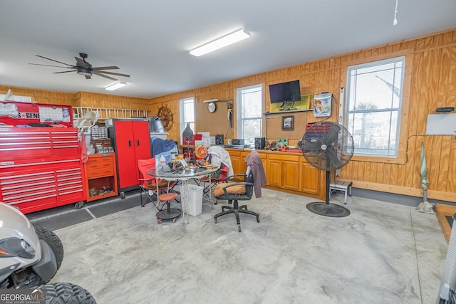 office space with ceiling fan, wood walls, and concrete flooring