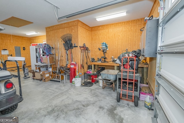 garage with a workshop area, wood walls, and electric panel