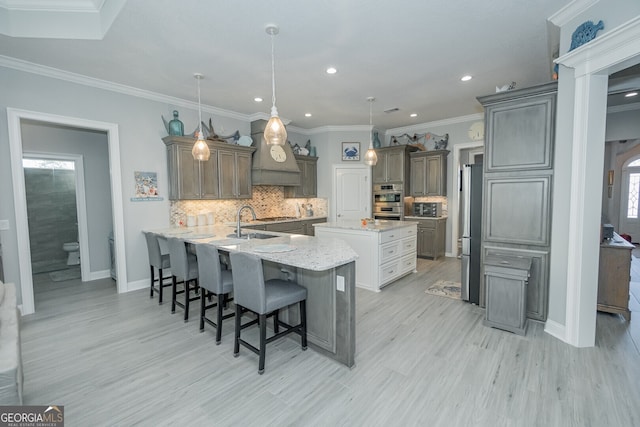 kitchen featuring hanging light fixtures, light stone counters, light hardwood / wood-style flooring, a breakfast bar area, and ornamental molding