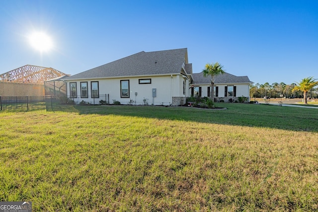 back of house featuring a lawn and glass enclosure