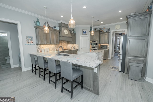 kitchen featuring kitchen peninsula, a kitchen breakfast bar, appliances with stainless steel finishes, sink, and hanging light fixtures