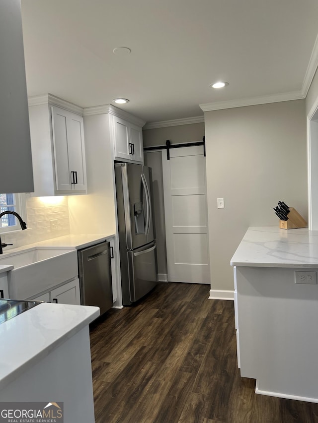 kitchen featuring stainless steel appliances, dark wood-type flooring, sink, a barn door, and white cabinetry