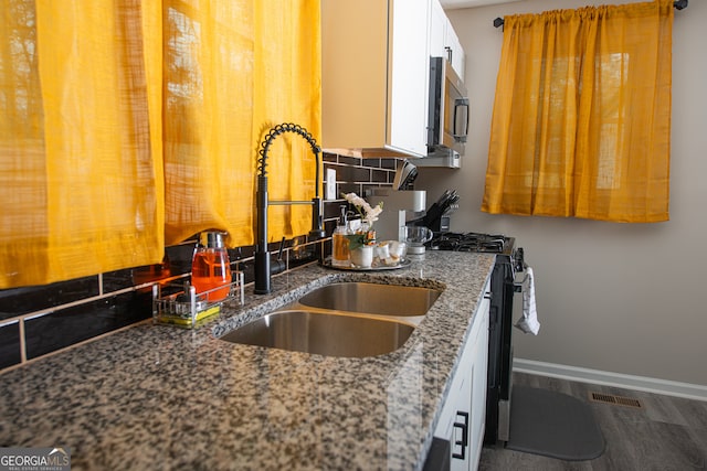 kitchen with stone counters, wood-type flooring, sink, tasteful backsplash, and white cabinetry