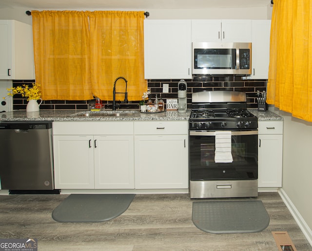 kitchen featuring white cabinets, sink, stainless steel appliances, and tasteful backsplash