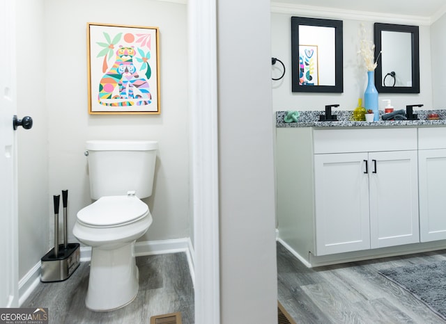 bathroom with toilet, hardwood / wood-style floors, vanity, and ornamental molding