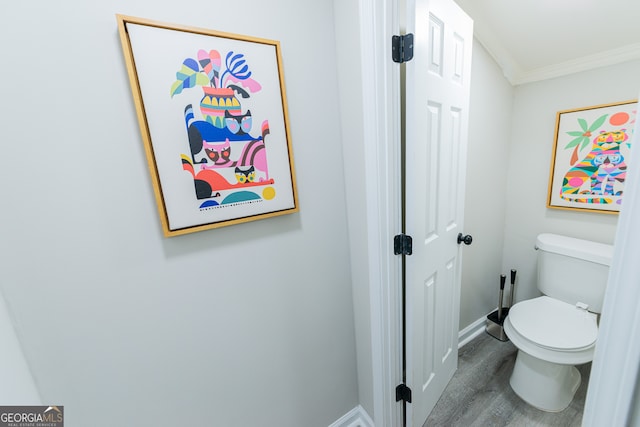 bathroom featuring hardwood / wood-style floors, toilet, and ornamental molding