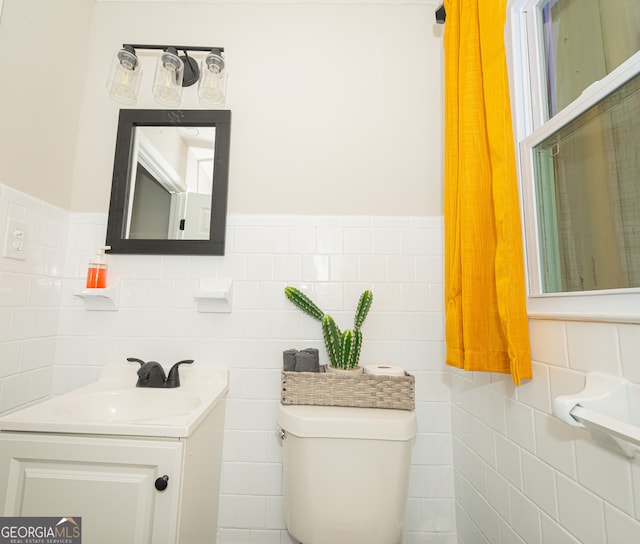 bathroom with vanity, toilet, and tile walls