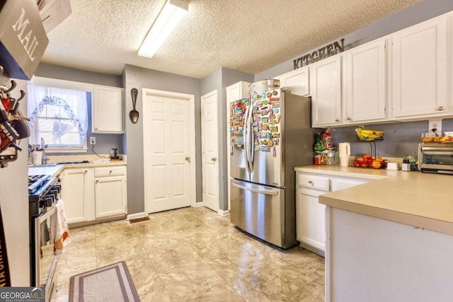 kitchen with a textured ceiling, stainless steel appliances, and white cabinetry