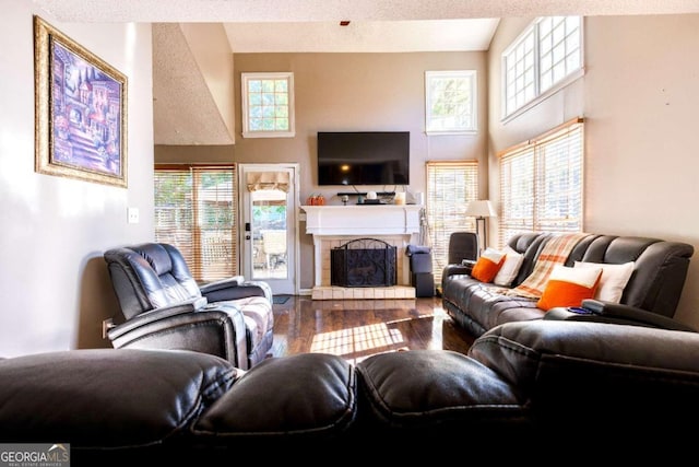 living room featuring a tile fireplace, hardwood / wood-style floors, a textured ceiling, and a healthy amount of sunlight