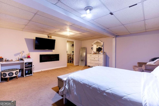 bedroom featuring light carpet, a drop ceiling, and ceiling fan