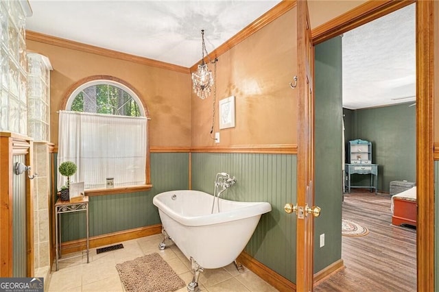 bathroom with a tub to relax in, tile patterned floors, and crown molding