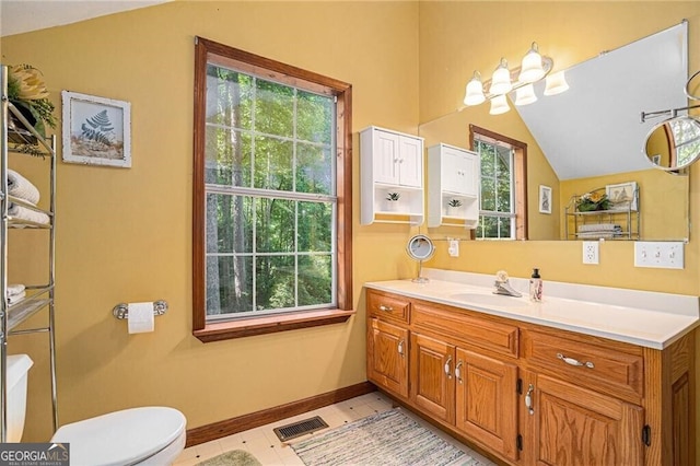 bathroom with tile patterned flooring, vanity, toilet, and lofted ceiling