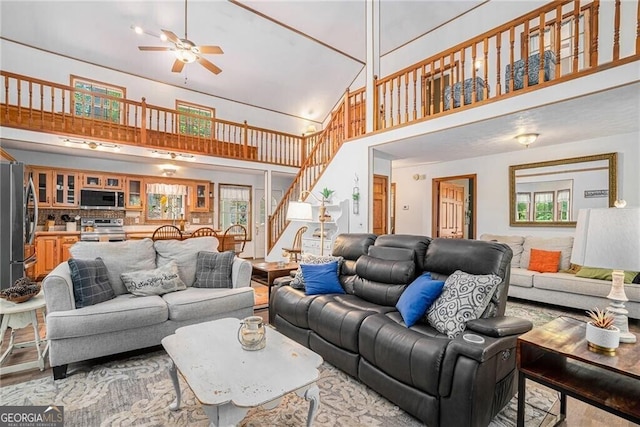 living room featuring ceiling fan, high vaulted ceiling, and light hardwood / wood-style flooring