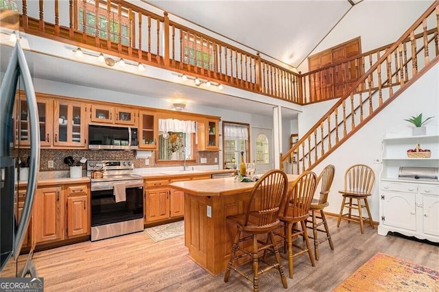 kitchen with decorative backsplash, stainless steel appliances, light hardwood / wood-style flooring, and a kitchen island